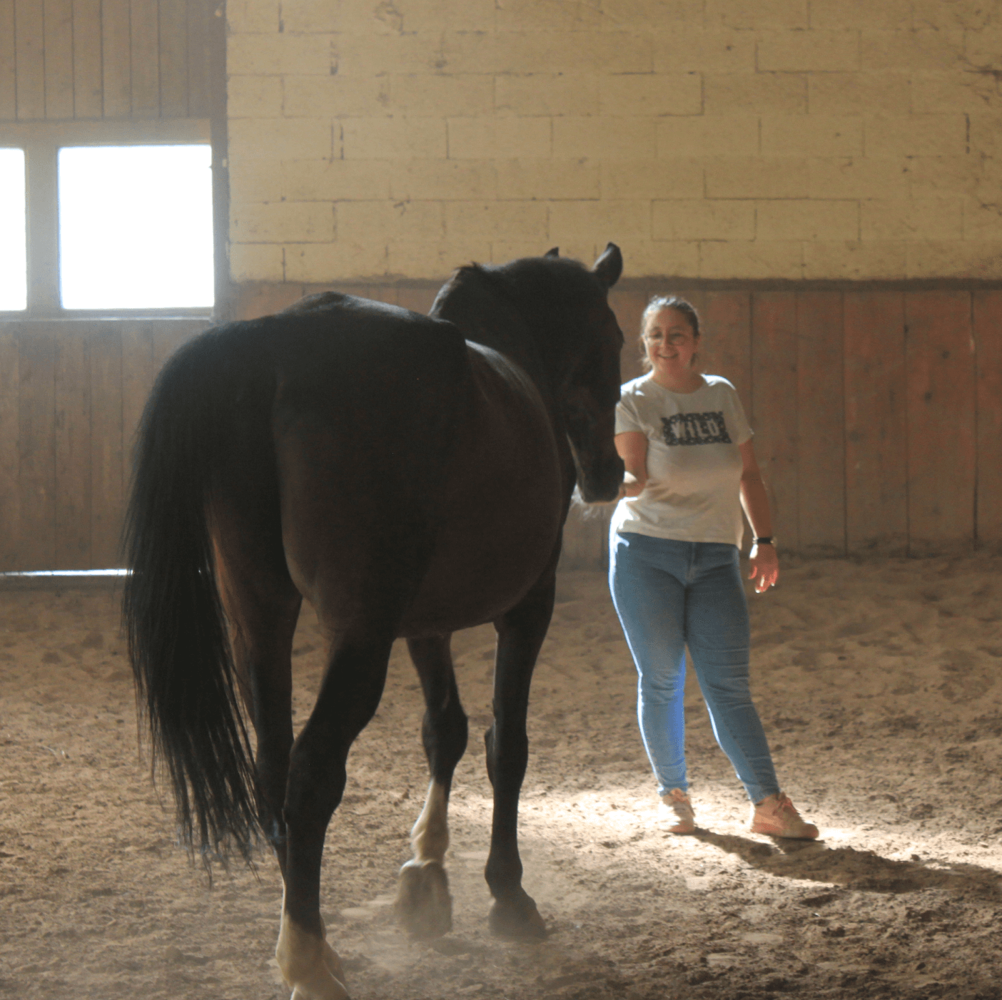 a woman standing next to a horse in a barn